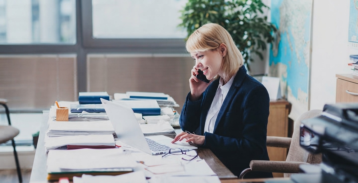 Professionnel effectuant un appel de relance courtois avec un dossier client en main dans un bureau